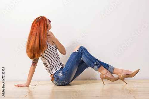Red-haired woman with tattoo touching her beautiful hair