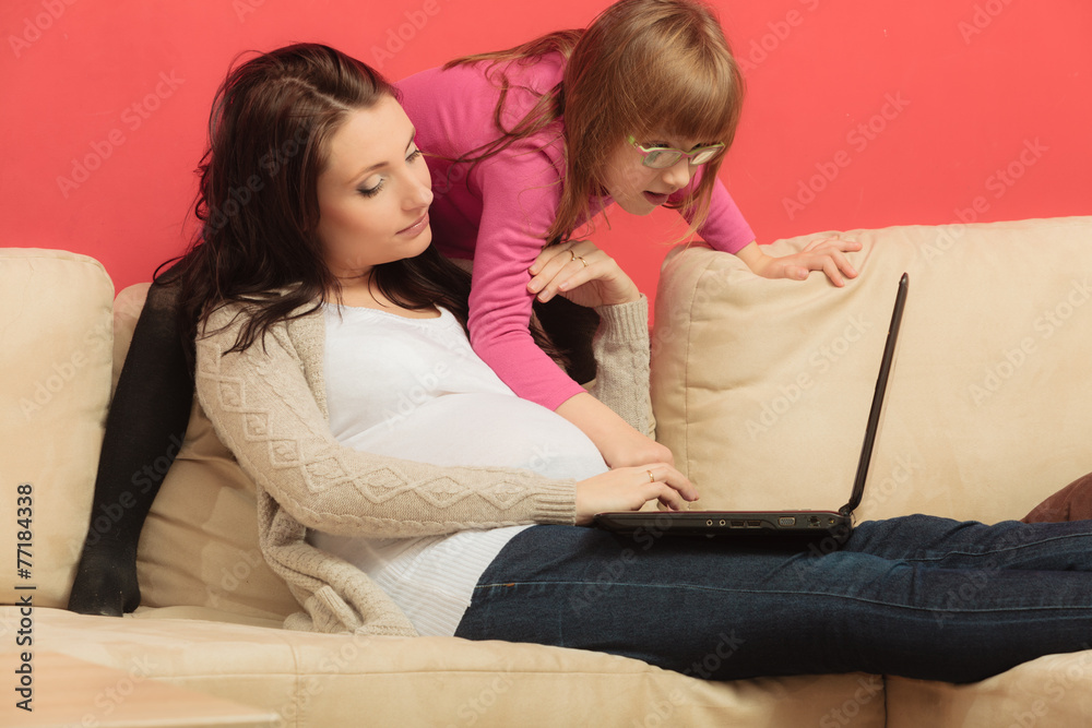 pregnant woman and her daughter using laptop