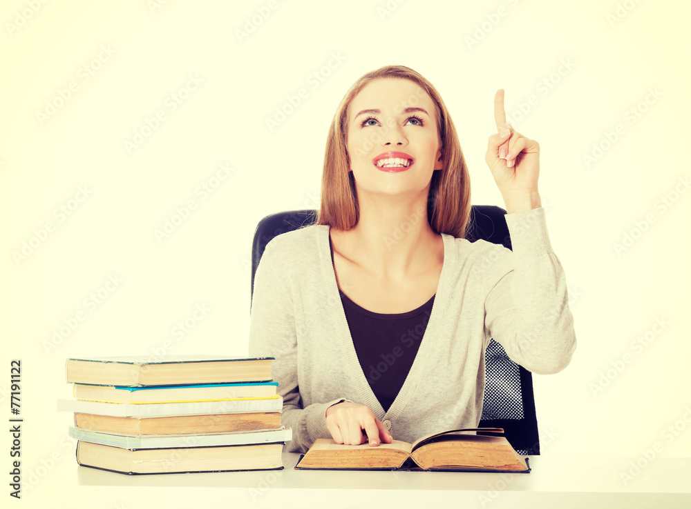 Woman sitting by stack of books and pointing up. Woman sitting by stack of books and pointing up.