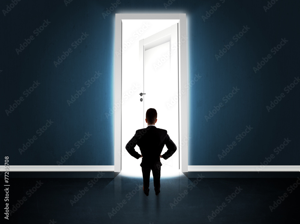 Business man looking at big bright opened door Business man looking at big bright opened door
