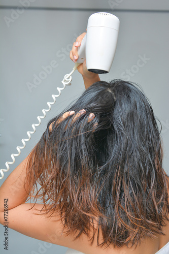 woman is blowing her hair with hair dryer