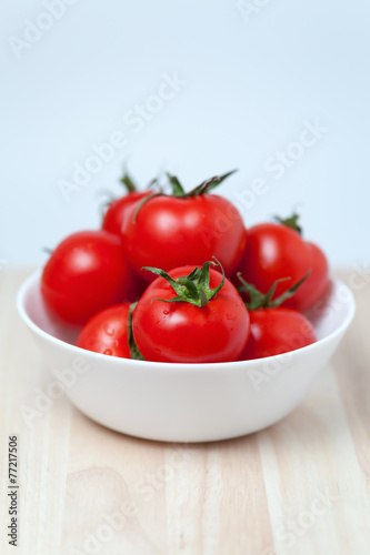 juicy red tomatoes in a bowl on wooden table