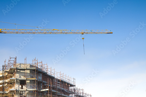 Tower crane in a blue background con scaffolding to work on the