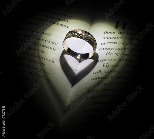 Golden ring in the open book fall some shadow like a hearts photo
