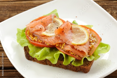 Rye bread sandwich with red fish, tomatoes and mustard