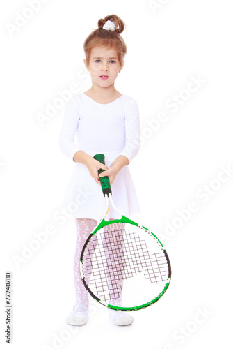 Little girl in sports dress holding a tennis racket.