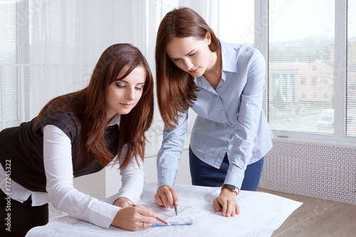 Female architects studying blueprints and make notes