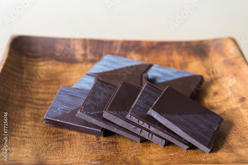 Fotografie Broken chocolate bar on wooden plate.