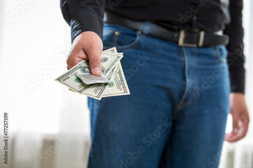 young man holding pack of dollars and condom