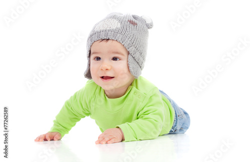 Beautiful baby with wool hat lying on the floor