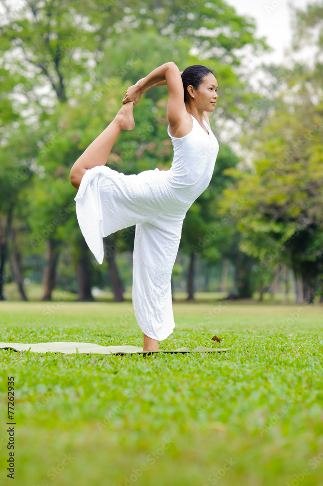 Beautiful woman practicing yoga in the park