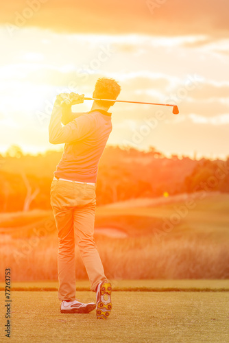 Golf player tee off at sunset