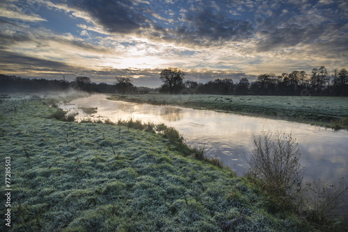 Countryside sunrise landscape with moody sky and flowing river