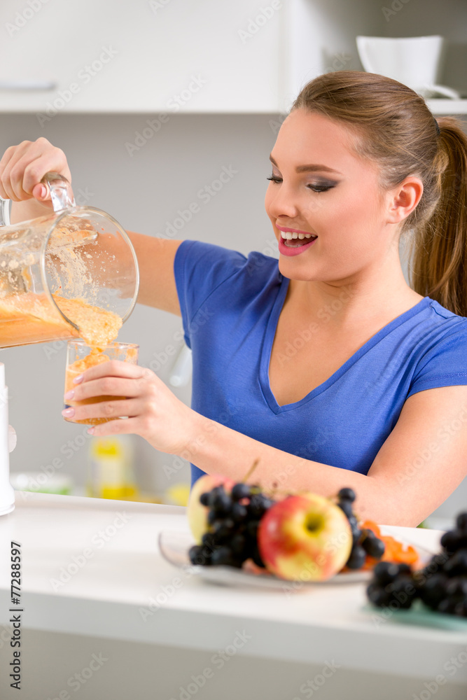 Smiling young woman holding a blender with a fruit smoothie Smiling young woman holding a blender with a fruit smoothie