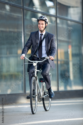 businessman riding bicycle by building