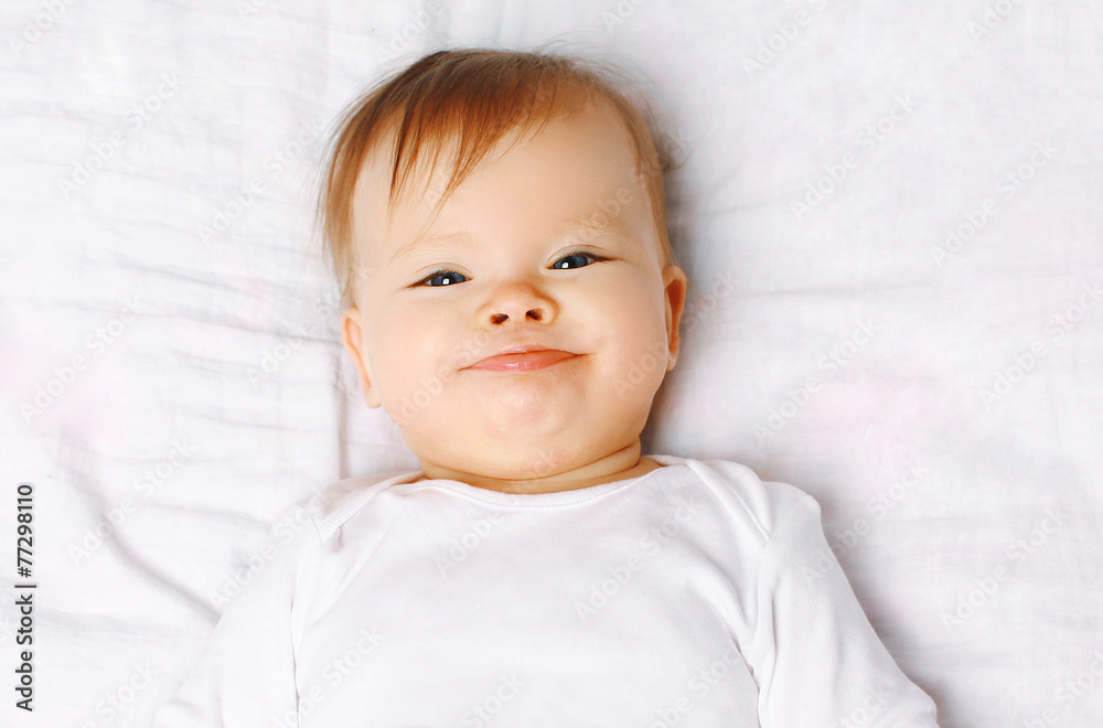Closeup portrait cute positive baby on the bed, top view Closeup portrait cute positive baby on the bed, top view