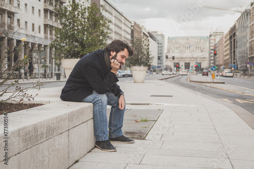 Young handsome bearded man posing in the city streets