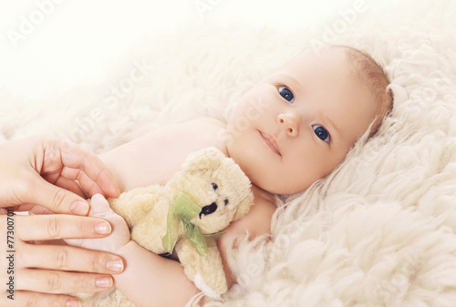 Little baby lying on the bed with teddy bear
