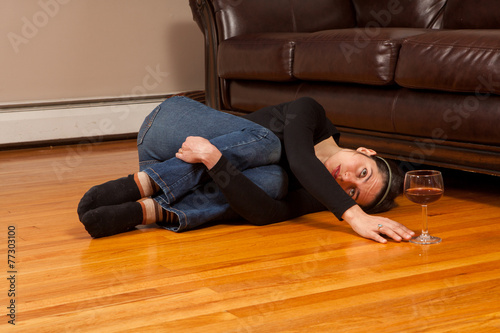 Young girl lying on floor reaching for a glass of wine. Addiction and Alcohol Abuse. photo