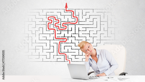 Business woman at desk with labyrinth and arrow
