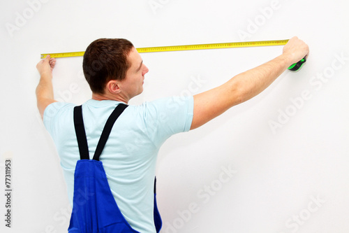 Young worker measure a wall