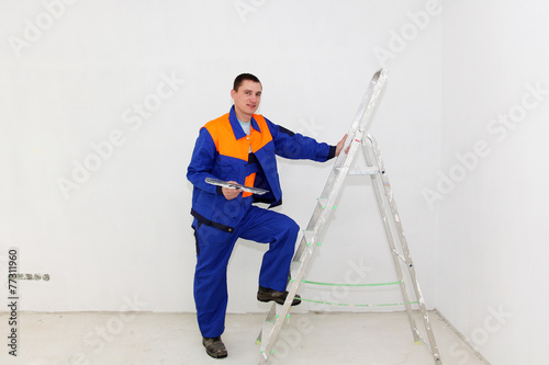 Young plasterer with ladder indoors