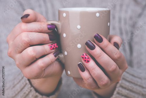 Woman with manicured nails holding a cup