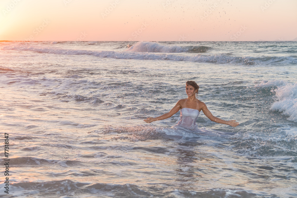 Young bride enjoys an accidental bath in the ocean waters.