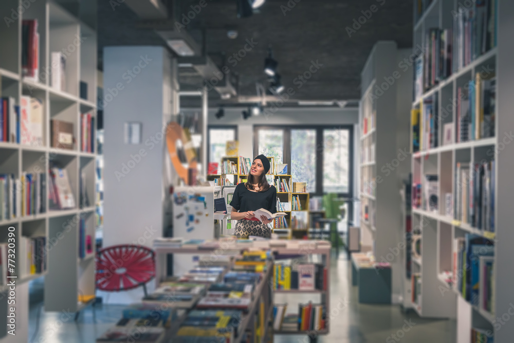 Fototapeta premium Beautiful young brunette posing in a bookstore
