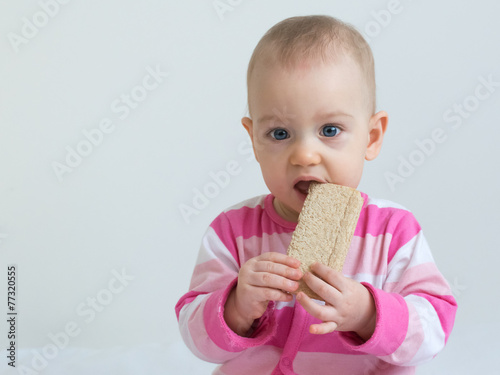 Infant eating  a slice of healthy  crunchy bread
