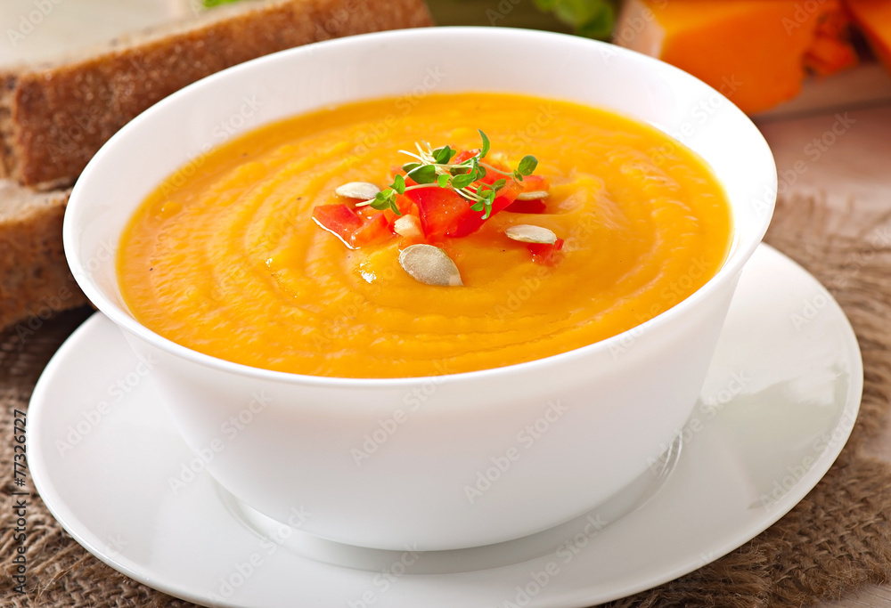 Delicious cream of pumpkin soup in a bowl on wooden table