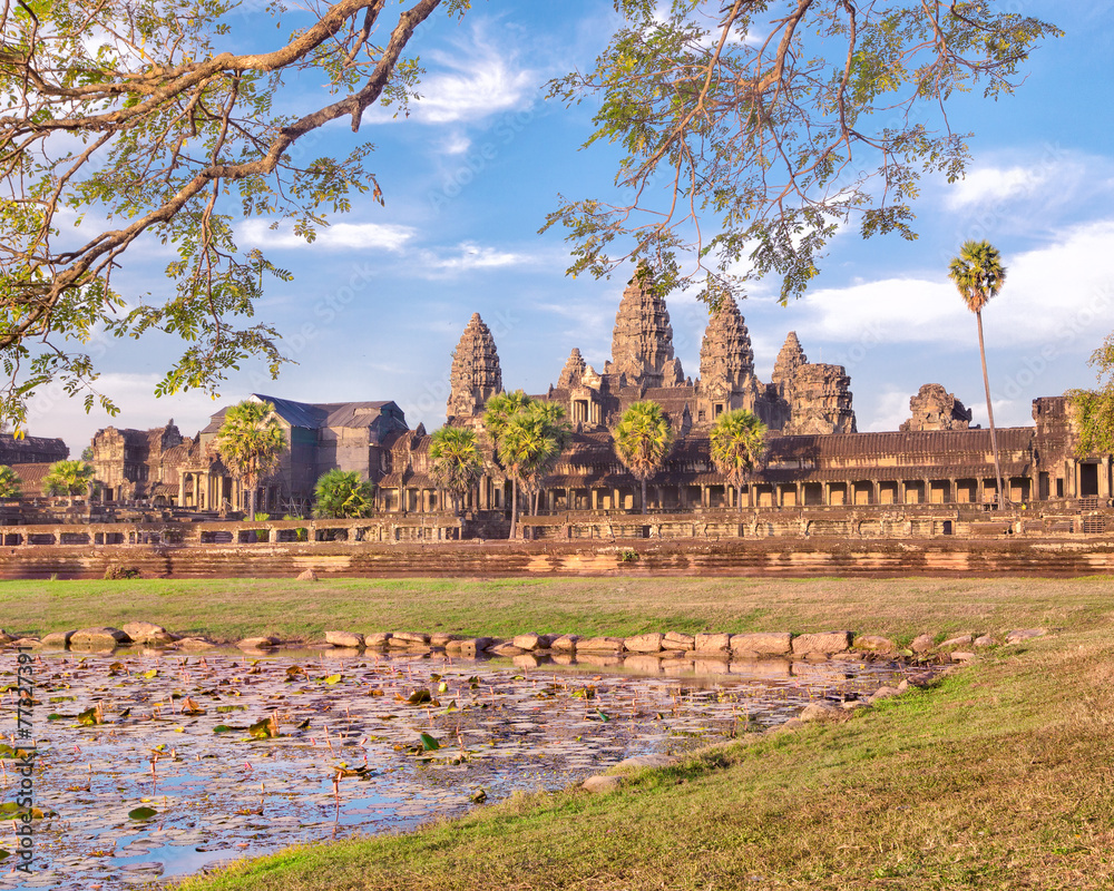 Fototapeta premium Angkor Wat temple reflecting in lake with flowers