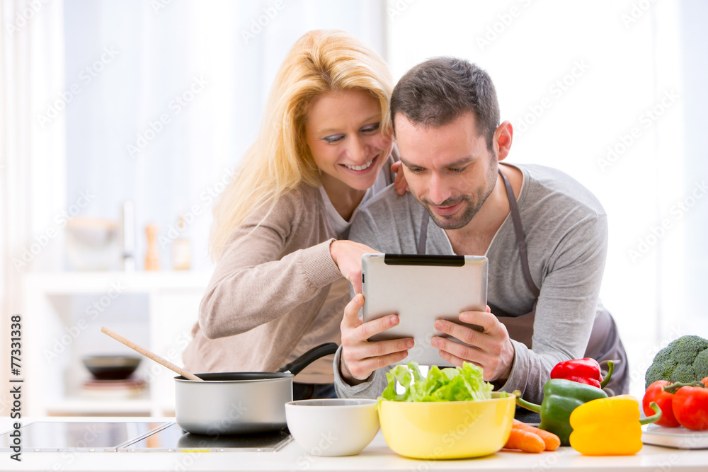 Young attractive couple reading recipe on a tablet Young attractive couple reading recipe on a tablet