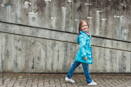 Adorable little girl walking in a city, wearing bright blue coat