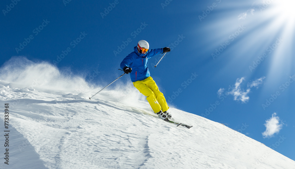 Male skier on downhill freeride with sun and mountain view