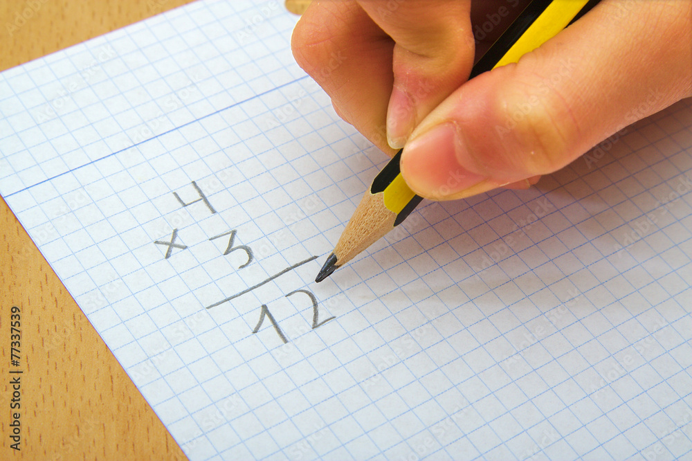 Closeup on the hands of a child doing maths. Multiply. School Closeup on the hands of a child doing maths. Multiply. School