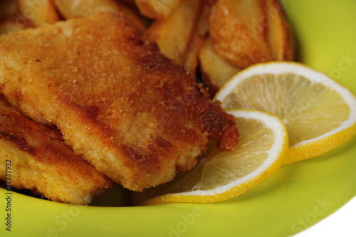 Breaded fried fish fillet and potatoes with sliced lemon