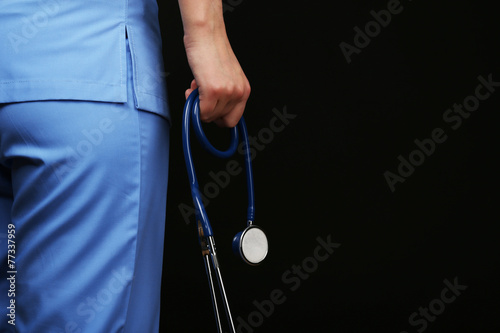 Doctor with stethoscope on black background