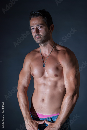 Muscle sexy man posing on bark background, showing his muscles