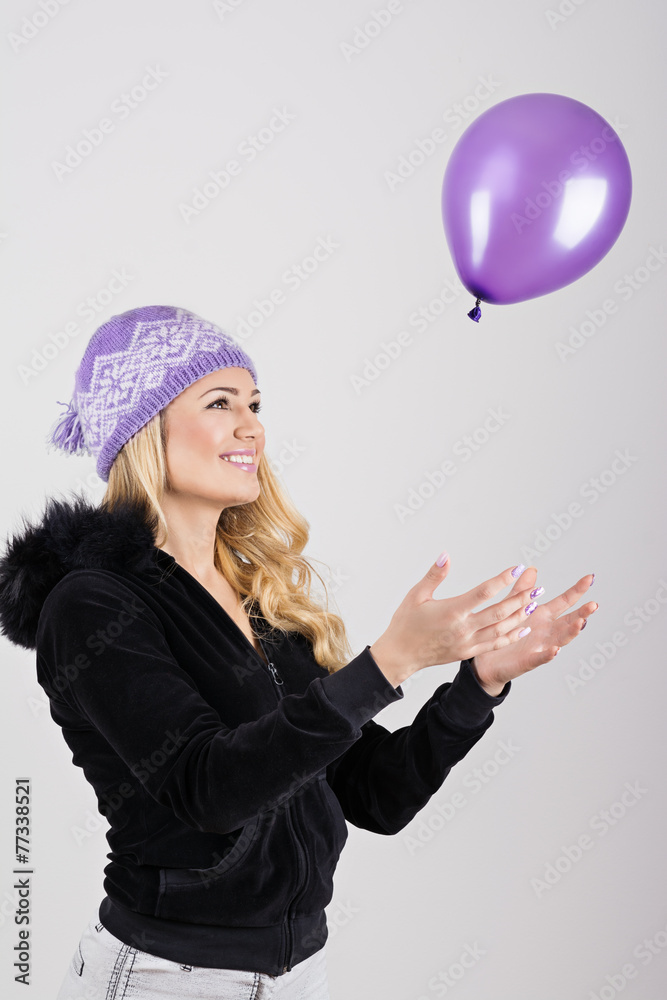 Fototapeta premium Teenage girl in purple knit hat playing with purple balloon
