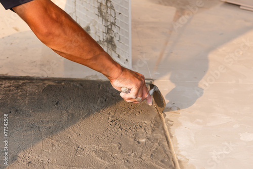 Labor installing tile floor for new house building