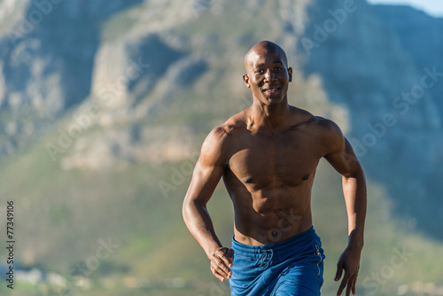Athletic, black male running along a road