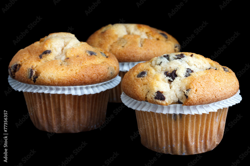 Three light chocolate chip muffins in wax liner on black. Three light chocolate chip muffins in wax liner on black.