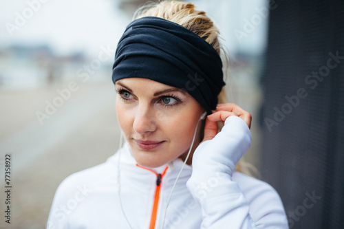 Foto Sportswoman wearing headband and listening to music on earphones