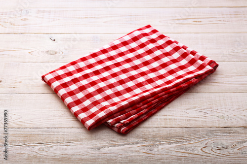Top view of checkered tablecloth on white wooden table.
