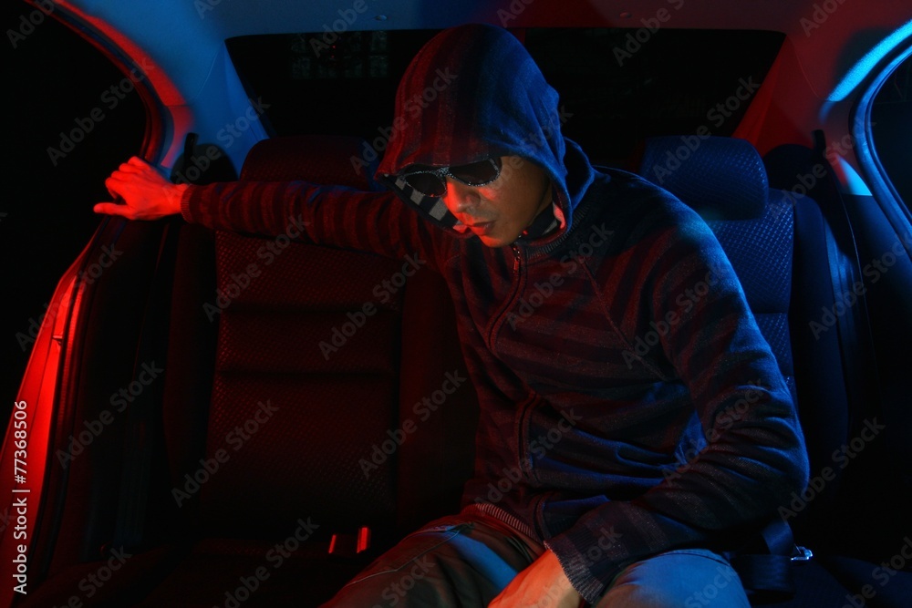 Man in the backseat of a car wearing a hoodie shirt