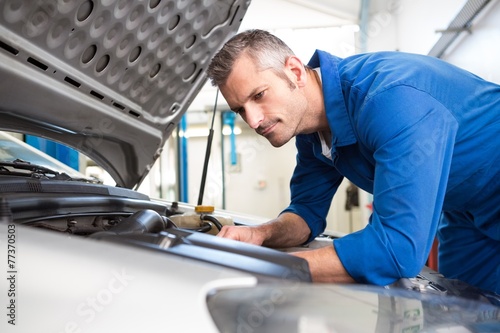 Mechanic examining under hood of car © WavebreakmediaMicro