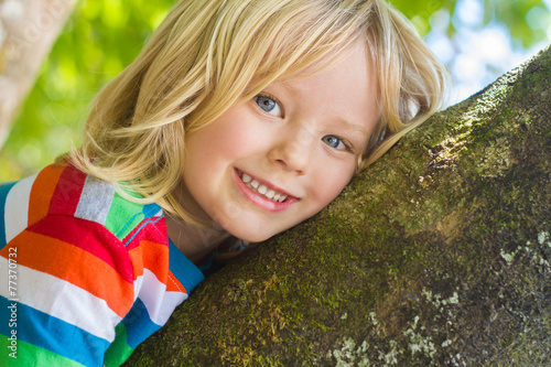 Cute happy child relaxing outdoors in tree
