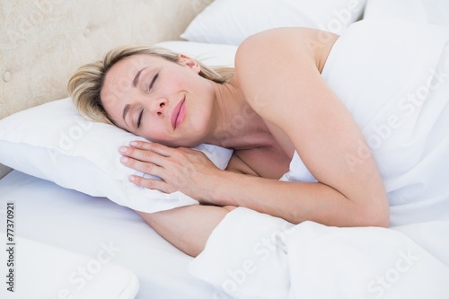 Cheerful blonde woman lying in bed