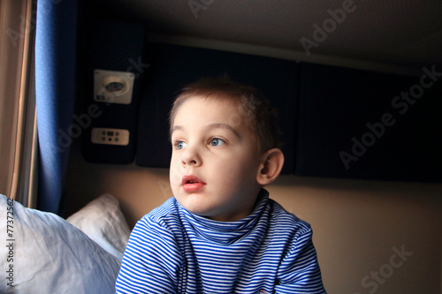 Мальчик смотрит в окно поезда в купе